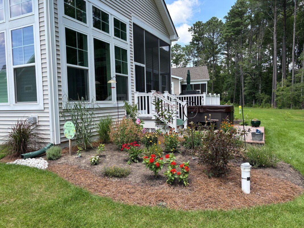 Same house with a nice native garden on the corner with bright red flowers.