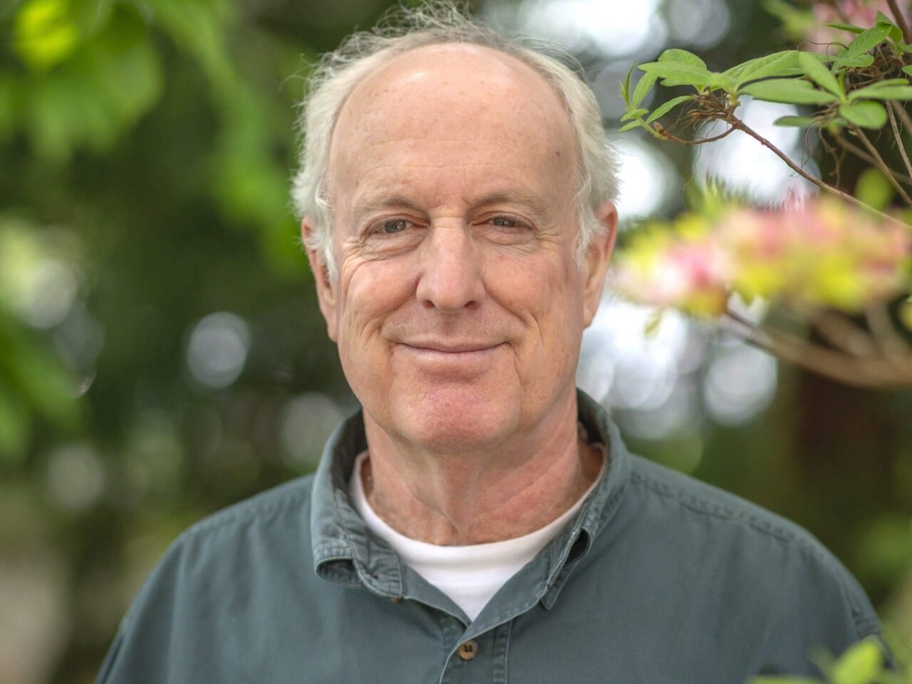 Face of a man outside in front of trees.