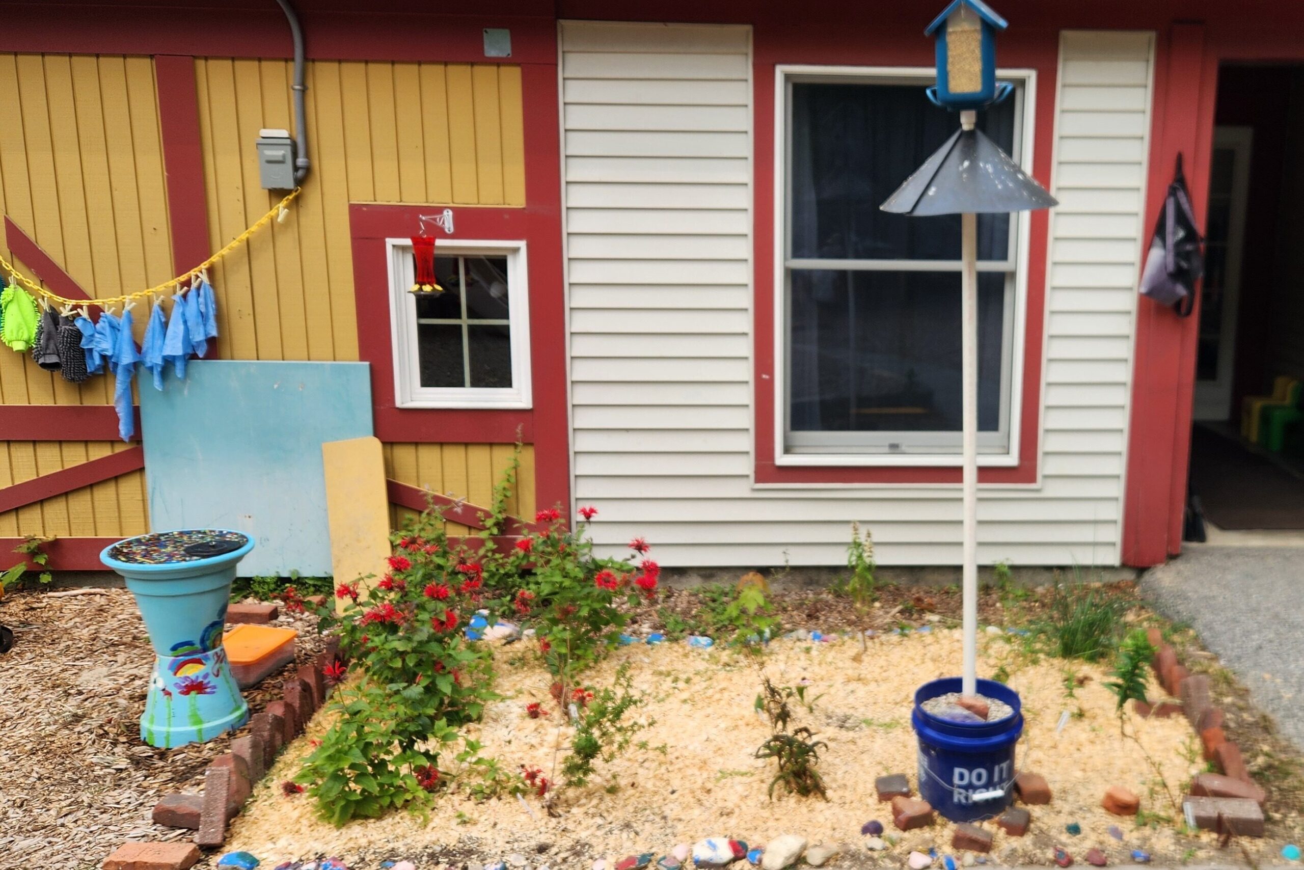 School yard with red flowers and bird feeders.