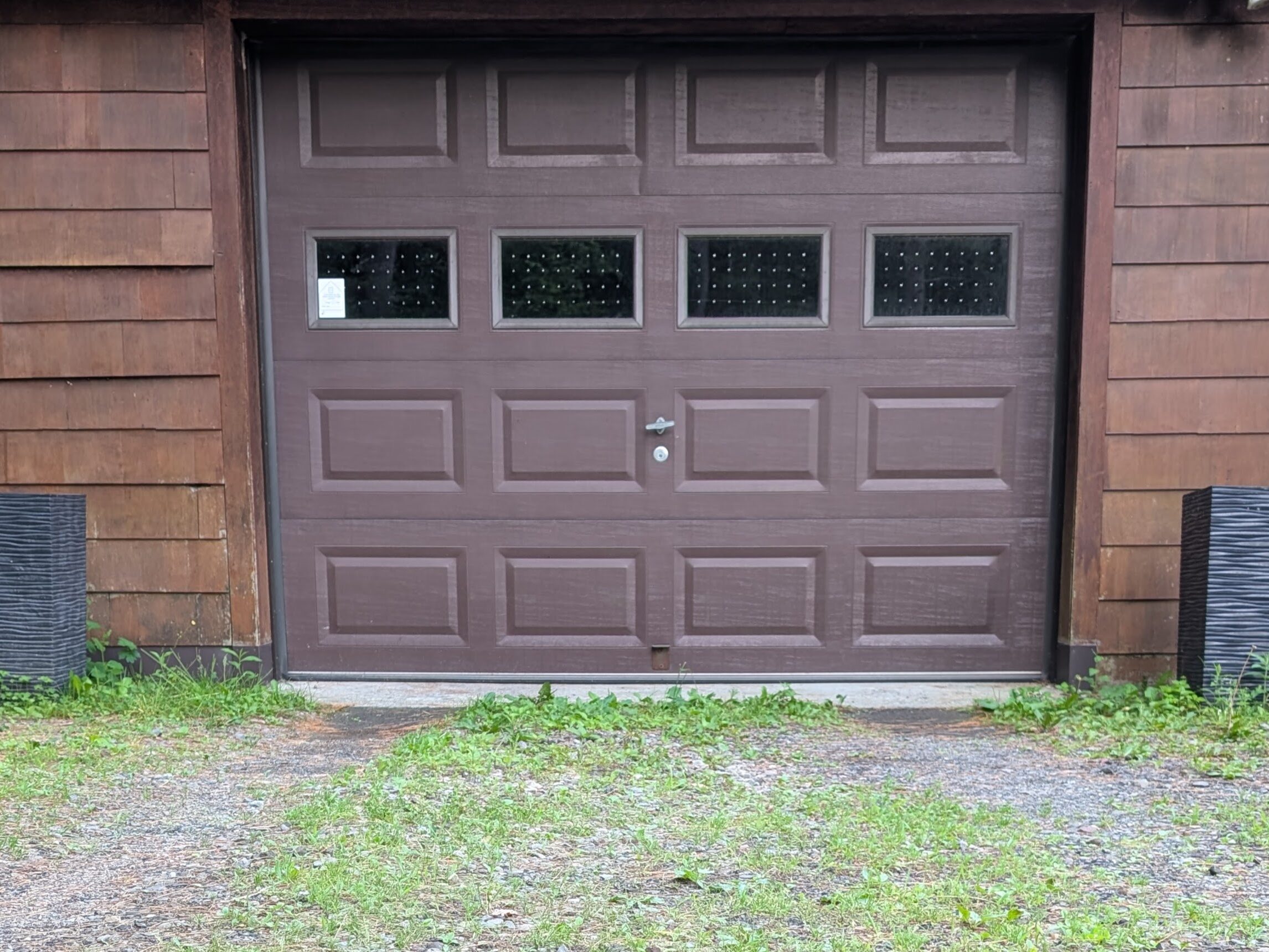 Front of a garage where weeds are growing on a driveway.