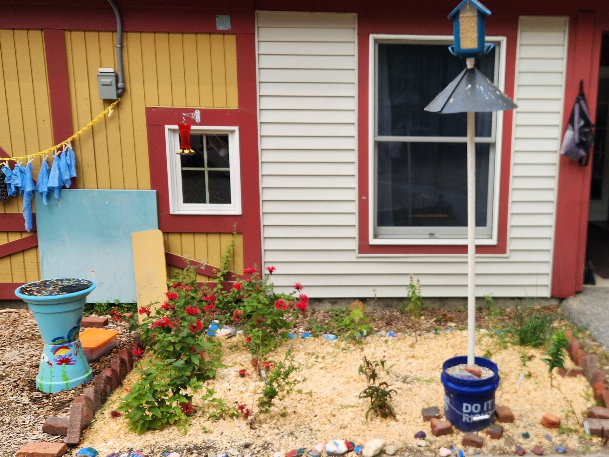 School yard with red flowers and bird feeders.