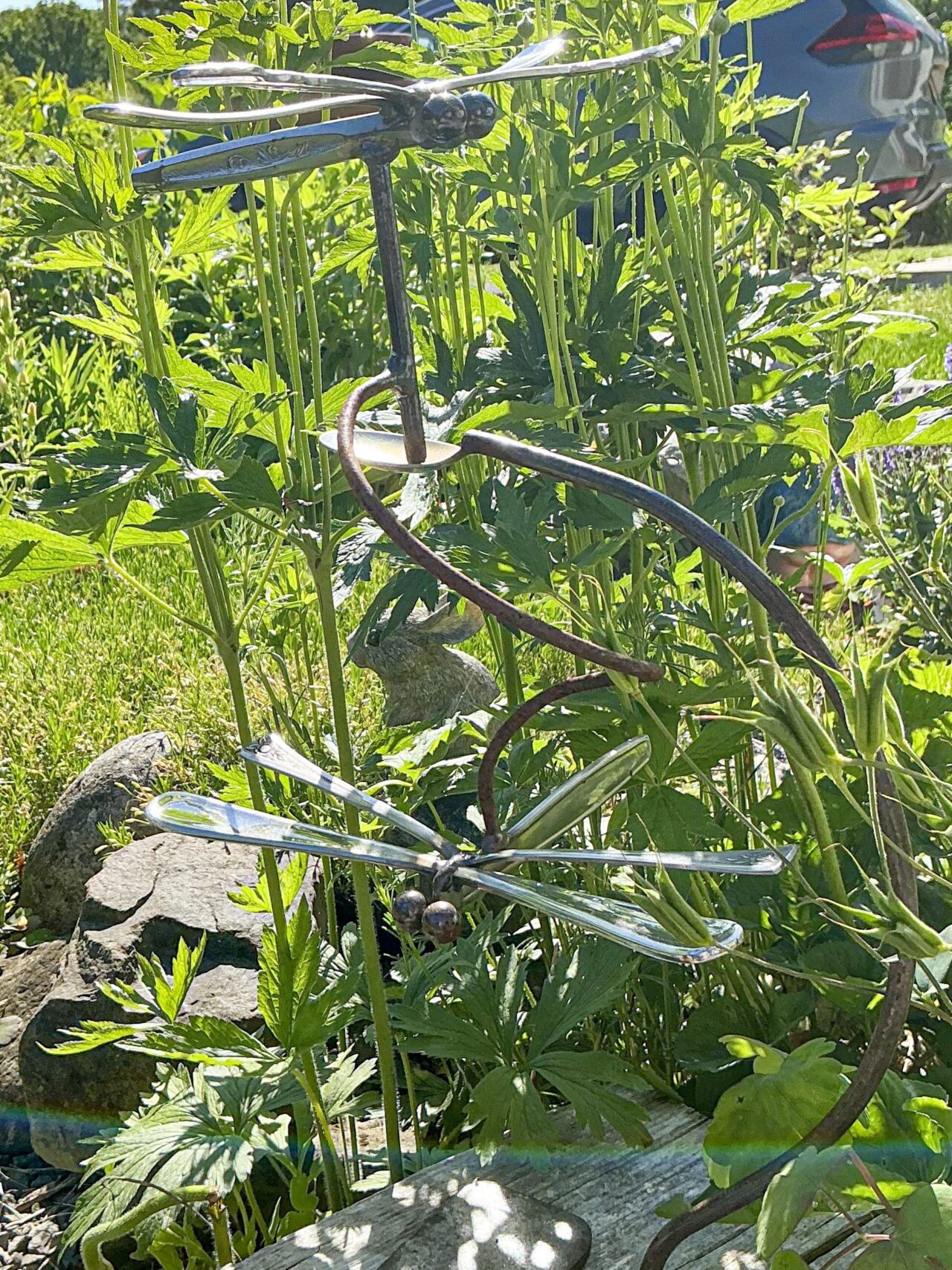 Metal dragonfly art among green plants